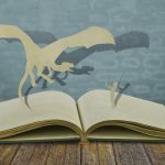Paper cut of dragon and child hold sword on old book