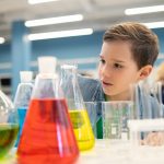 Boy examining flasks with colored liquids