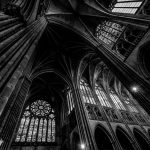 Low angle shot of a cathedral ceiling with windows in black and white