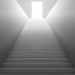 White staircase with light from open door on top