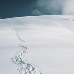 Beautiful shot of a snow landscape with foot tracks in the snow under the blue sky