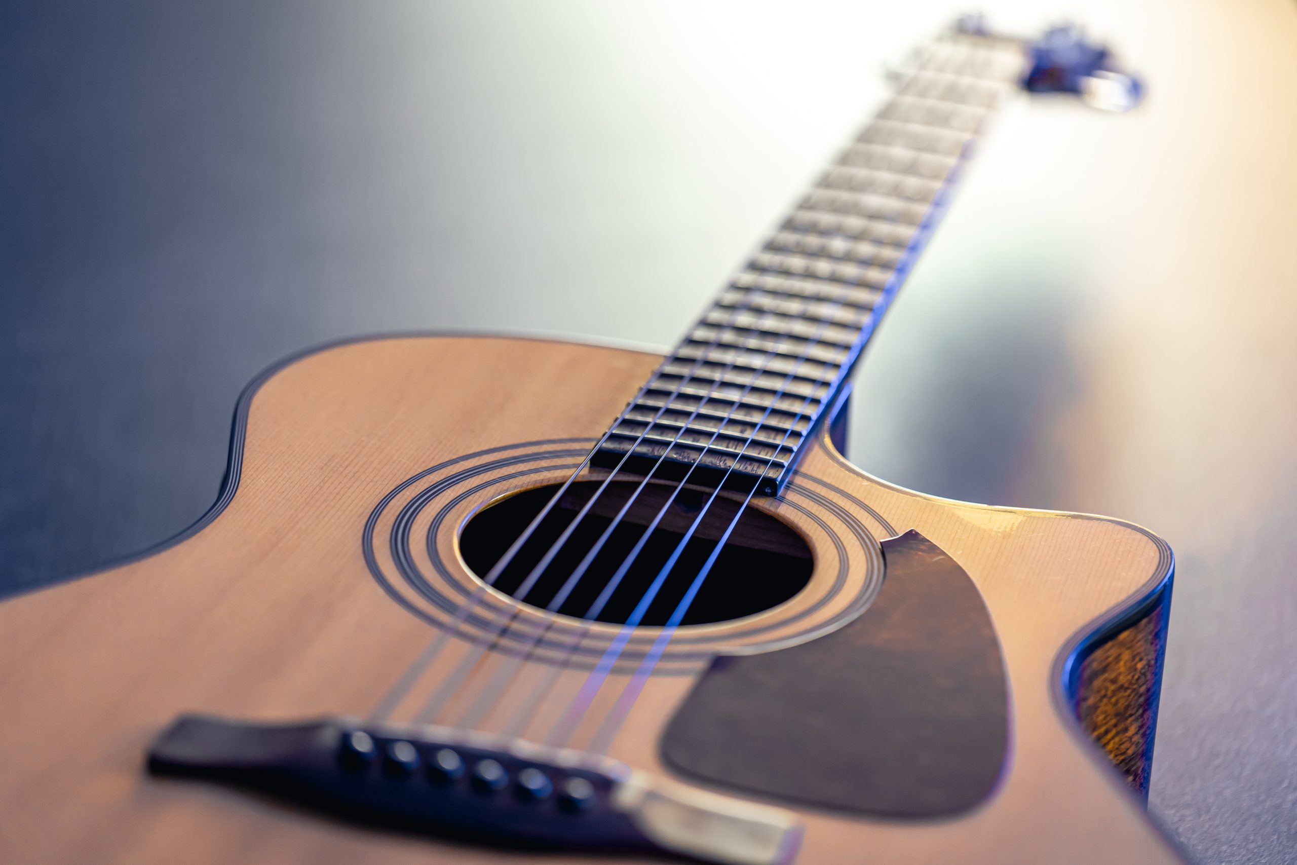 Acoustic guitar, music instrument resting against a dark black background.